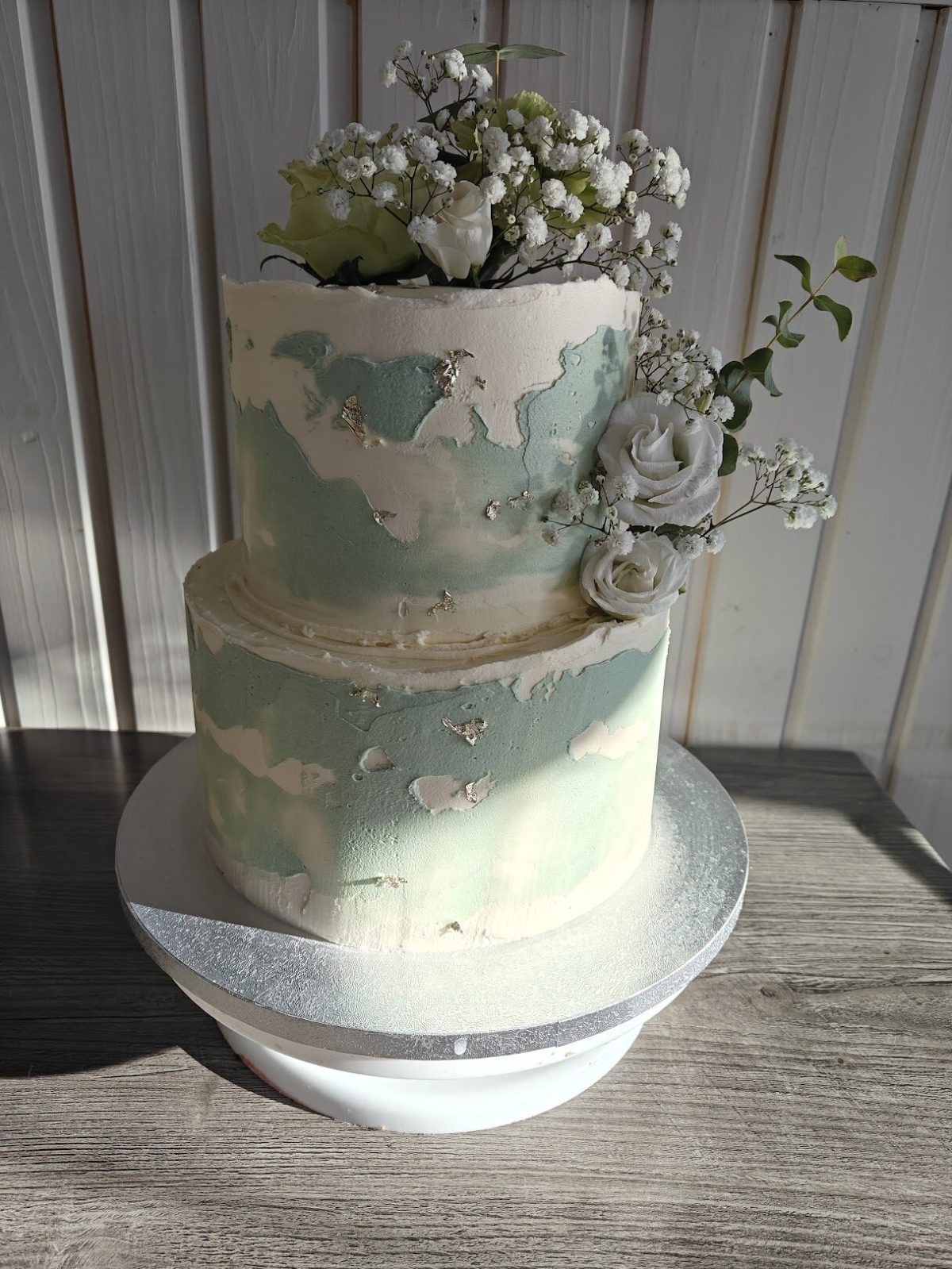 Käsintehty kaksikerroksinen juhlakakku kukkakoristein Bake'N Decor Cafessa